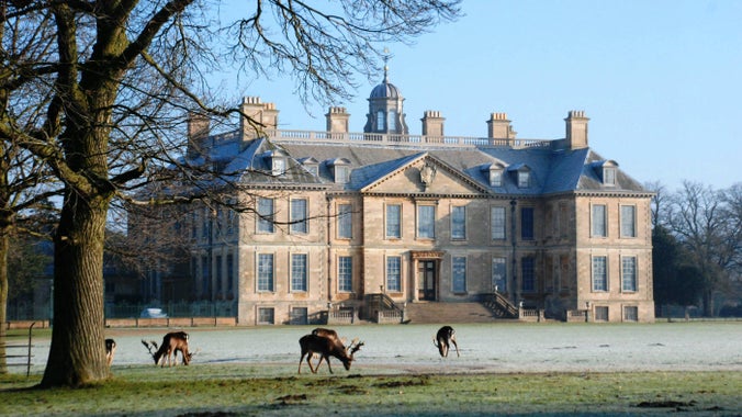 View of the south front of Belton House, with winter frost and deer grazing